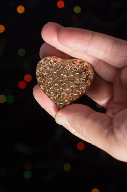 Kalp şekli simgesi üzerinde bokeh ışık elinde