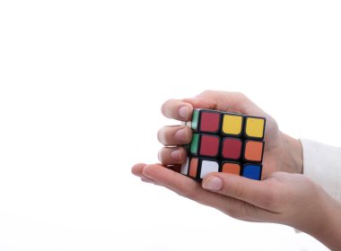 Beyaz arka planda elinde bir Rubik küpünü tutan çocuk