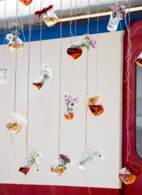 İplere asılı çiçekli bitkisel çay şişeleri