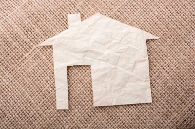 Tuvalin arka planında kağıttan yapılmış küçük bir ev şekli.