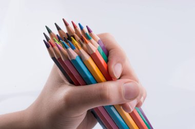 Beyaz arkaplanda el ele tutuşan renkli kalemler