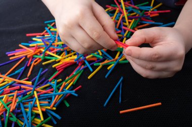 Beyaz arka planda yaratıcılık için renkli tahta çubuklarla oynayan çocuk