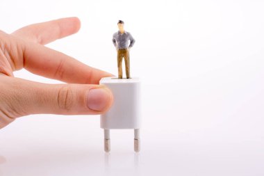 Bir insan figürü beyaz bir bağdaştırıcı üzerinde tutan el