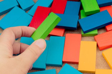 Çeşitli renklerin ahşap bloklarından birini tutarken