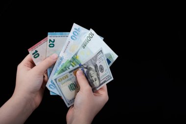 El ele tutuşan Amerikan doları banknotları siyah arka planda izole edilmiş.