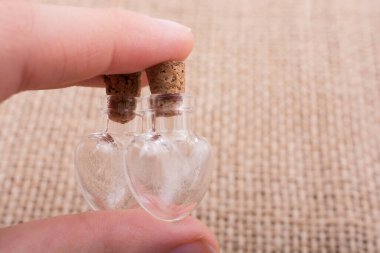 Kalp şeklinde cam şişeler el ele tutulur.