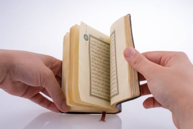 Beyaz arka planda Kuran 'ı el ele tutuşarak.
