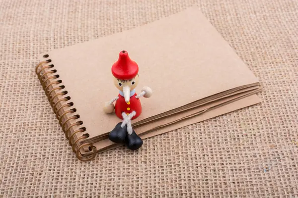 stock image Pinocchio sitting on notebook on a canvas background