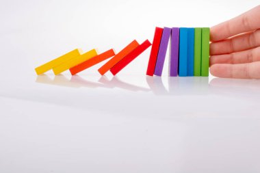 Beyaz arka planda el ele tutuşan renkli domino taşları