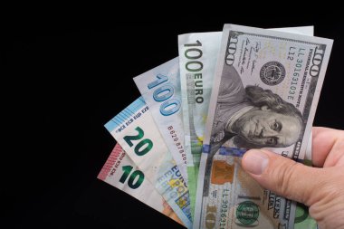 El ele tutuşan Amerikan doları banknotları siyah arka planda izole edilmiş.