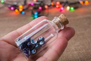 Hatıra olarak şişede nazar boncuğu tutan el.