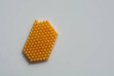 Sarı renkli böcek yumurtaları beyaz arka planda neredeyse mükemmel bir altıgen oluşturuyor.