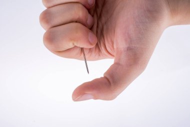 Beyaz arka planda bir iğne tutan el.