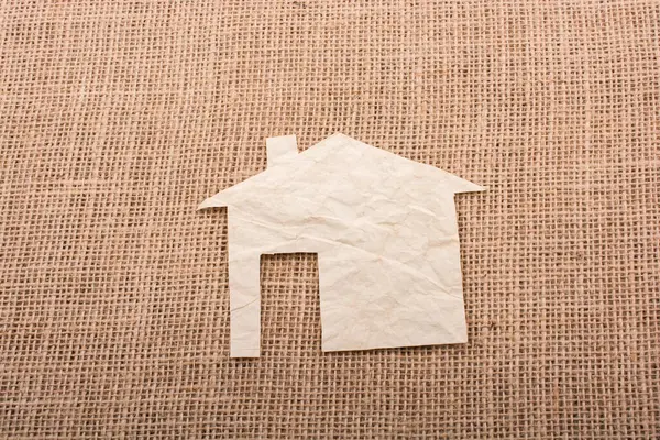 Tuvalin arka planında kağıttan yapılmış küçük bir ev şekli.