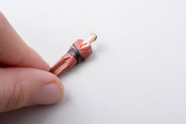 Bir ipe bağlanmış insan modelinin minicik biblosunu tutuyorum.