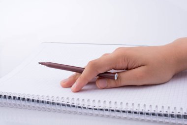 El üstünde bir defter beyaz zemin üzerine kalemle yazma