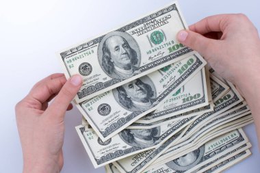 İnsan eli, Amerikan doları banknotunu beyaza izole edilmiş olarak tutuyor.