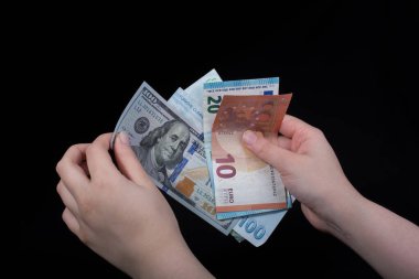 El ele tutuşan Amerikan doları banknotları siyah arka planda izole edilmiş.