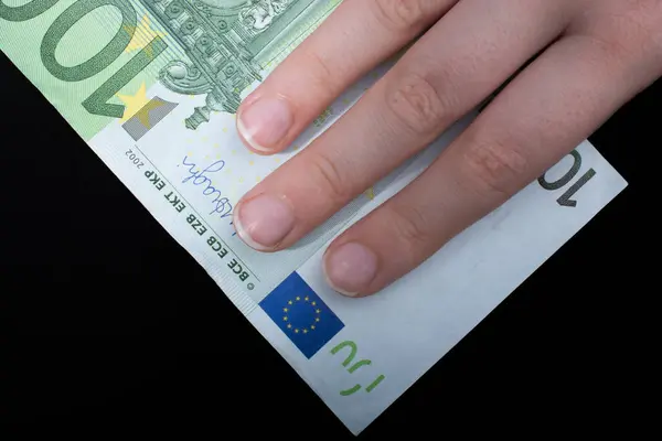 stock image Hand holding 100 euro money  cash isolated on black background