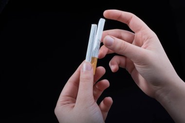 Siyah arka planda sigara tutan bir el var.