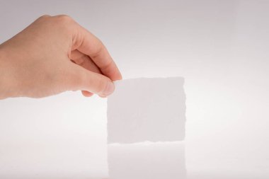 Beyaz bir arka plan üzerinde yırtık bir kağıt parçası tutan el