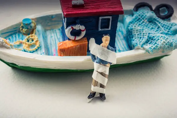 stock image Tiny wrapped figurine of man model beside a model boat