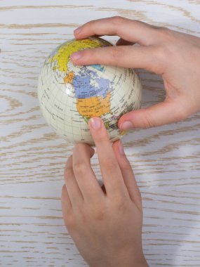 Üzerinde harita olan bir küreyi tutan el.
