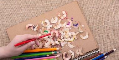 Kalem talaşı olan bir defterin üzerinde Renkli Kalem 'i tutarken