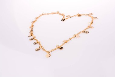 Ellerinde bir zincir üzerinde dizilmiş altın renk suratlar bir kalp şekli oluşturur