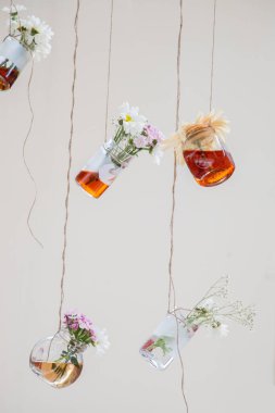 İplere asılı çiçekli bitkisel çay şişeleri