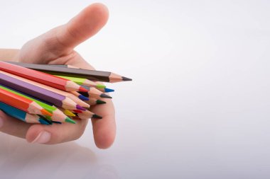 Beyaz arkaplanda el ele tutuşan renkli kalemler