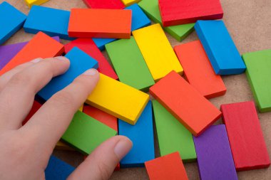 Çeşitli renklerin ahşap bloklarından birini tutarken