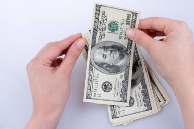 İnsan eli, Amerikan doları banknotunu beyaza izole edilmiş olarak tutuyor.