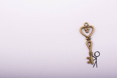 Beyaz arka planda kalp şeklinde anahtar taşıyan bir adam.