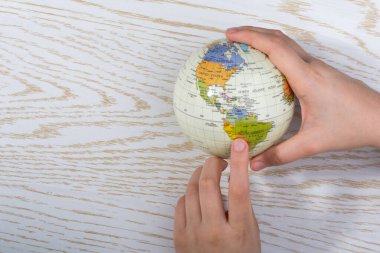 Hand holding a globe  with map on it clipart