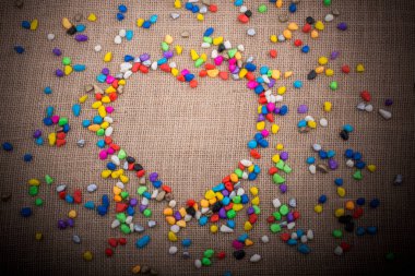 Renkli küçük çakıl tuval zemin üzerinde bir kalp şeklini