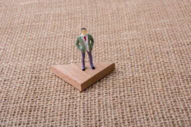 Bir üçgen parça tahta üzerinde adam heykelcik duran