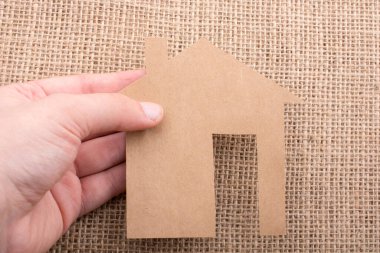 Tuvalin arka planında bir bez evi tutan el.