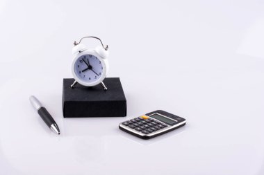 çalar saat, hesap makinesi, kalem ve defter beyaz bir arka plan üzerine yerleştirilen