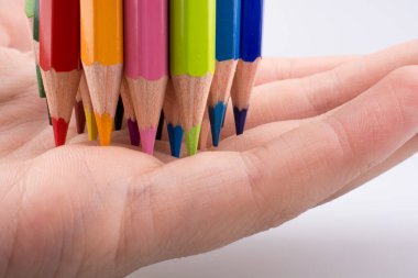 Beyaz arkaplanda el ele tutuşan renkli kalemler