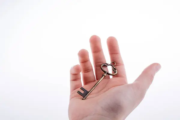 stock image hand holding a  retro styled metal key  on a white background