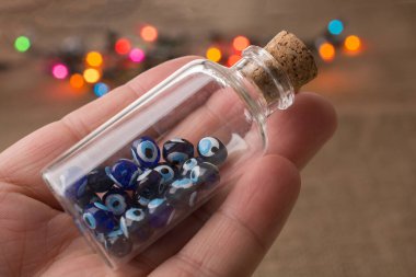 Hatıra olarak şişede nazar boncuğu tutan el.