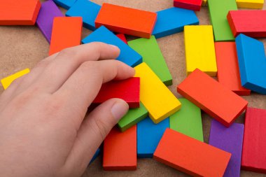 Çeşitli renklerin ahşap bloklarından birini tutarken