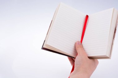 Beyaz bir arkaplanda elinde bir defter var.