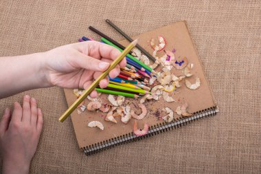 Kalem talaşı olan bir defterin üzerinde Renkli Kalem 'i tutarken