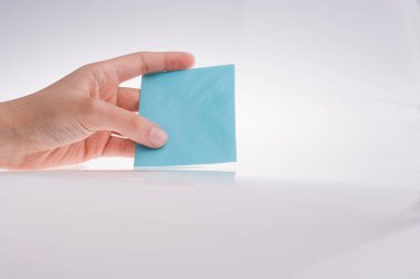 Beyaz bir arka plan üzerine açık mavi renk dikdörtgen kağıt tutan el