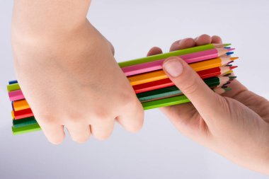 Beyaz arkaplanda el ele tutuşan renkli kalemler