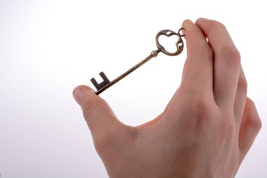 Beyaz arka planda eski moda metal bir anahtar tutan el.