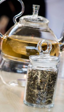 Cam çaydanlıkta demlenmiş bitki çayı ve şişede çay bitkisi.