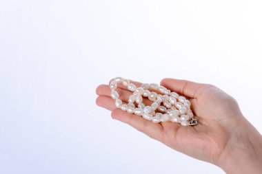 Bir inci kolye beyaz bir arka plan üzerinde tutan el